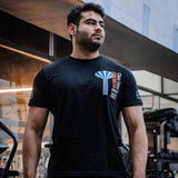 Man wearing a black t-shirt with a logo in an indoor setting