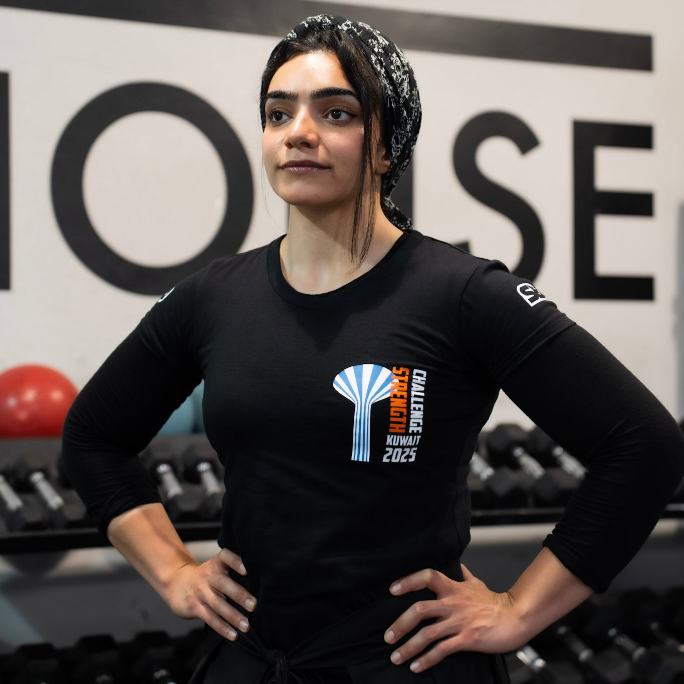 Person wearing a black t-shirt with a logo in a gym setting
