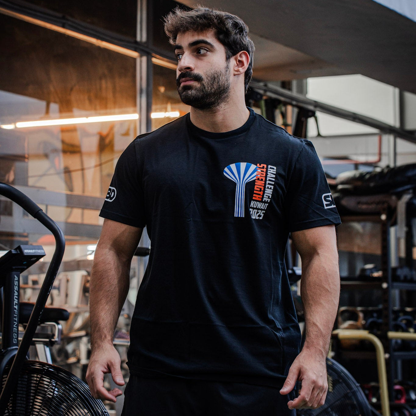 Man wearing a black t-shirt with a logo in an urban setting